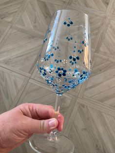 a hand holding a wine glass with blue and white confetti on it