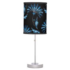 a black lamp with blue flowers on the bottom and a white base is lit up