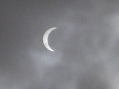 the moon is seen through some clouds on a cloudy day