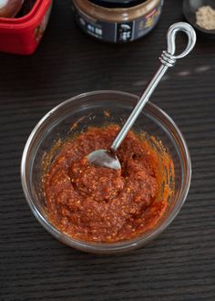 a glass bowl filled with sauce on top of a wooden table