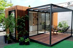 a small house made out of wood and glass with a patio attached to the side