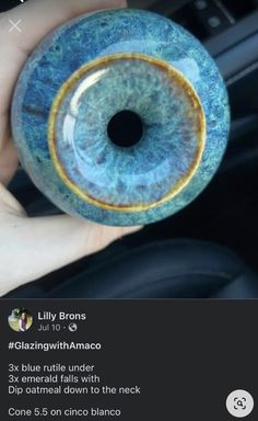 someone is holding up a fake blue eyeball in their hand and it looks like they are looking at the camera