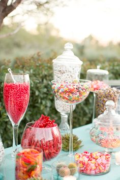 a table topped with lots of candy and candies next to a glass filled with wine