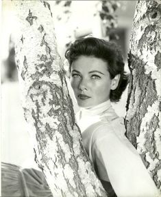 an old photo of a woman peeking out from behind a tree