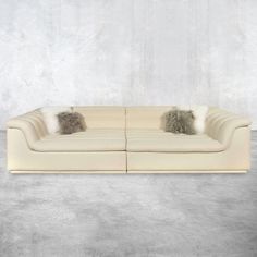 a white couch with two pillows on it and a gray wall in the back ground