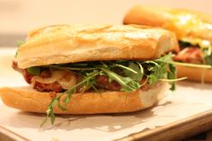 two sub sandwiches sitting on top of a cutting board