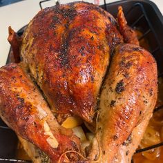 a roasted chicken in a roasting pan with potatoes