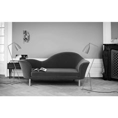 a black and white photo of a living room with a couch, lamp and fireplace