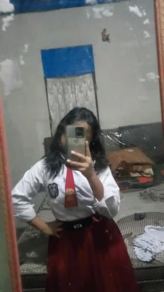 a woman taking a selfie in front of a mirror while wearing a red tie