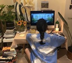 a woman sitting in front of a computer on top of a desk covered in a blanket