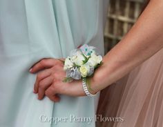 two bridesmaids are holding hands with flowers on their arm and one is wearing a light blue dress