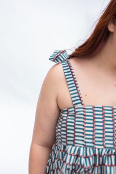 a woman with red hair wearing a blue and white striped dress holding a cell phone to her ear