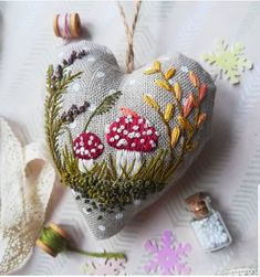 a heart shaped ornament with mushrooms on it and thread spools next to it