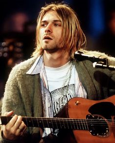 a man sitting in front of a microphone holding a guitar