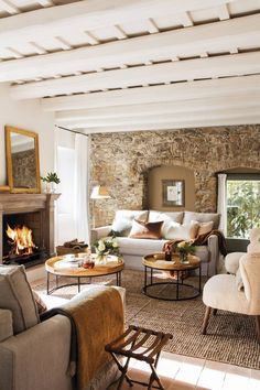 a living room filled with furniture and a fire place next to a stone wall covered in windows