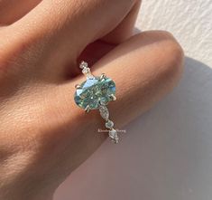 a woman's hand with a ring on it that has an aqua blue stone in the middle