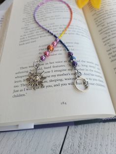 an open book with a beaded necklace on it and a flower in the background