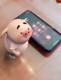 a small toy pig standing next to an iphone