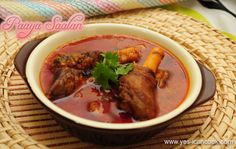 a bowl filled with meat and vegetables on top of a woven table cloth next to a spoon