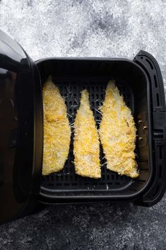 three pieces of corn on the cob in an air fryer with grated parmesan cheese