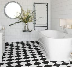 a black and white checkered floor in a bathroom with an oval mirror above the bathtub