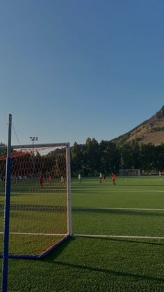 a soccer field with several players on it and a mountain in the backround