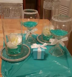 there are three vases with flowers in them on the table and one has a blue gift box