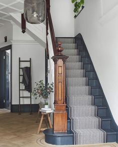 a staircase with blue and white carpeting next to a wooden clock on the wall