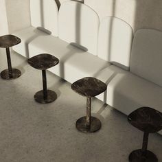 four chairs and two tables in front of a white couch with long shadows on the wall