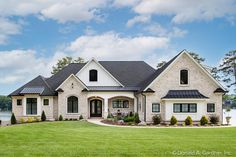 a large white house sitting on top of a lush green field next to a lake