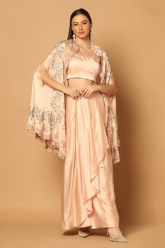 Soft peach cape with multicolor floral embroidered motifs. Comes with strappy crop top and draped skirt set.
Components: 3
Pattern: Embroidery
Type Of Work: Thread and Sequin
Neckline: Scoop
Sleeve Type: Sleeveless
Fabric: Satin
Color: Peach
Other Details: 
Open front cape with asymmetrical hem
Waistband embroidered skirt
Skirt with tie up on the side
Cape with scallop edge
Occasion: Destination Wedding - Aza Fashions Side Cape, Floral Cape, Peach Skirt, Cape Set, Embroidered Cape, Satin Embroidery, Satin Hands, Embroidered Motifs, Strappy Crop Top