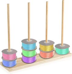 four spools of colored thread are on a wooden stand with two skewers