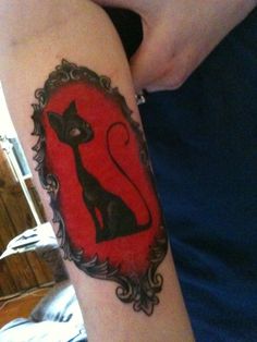 a woman's arm with a cat tattoo on it and an oval frame around her