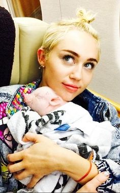 a woman holding a baby in her arms while sitting on an airplane with the seat down