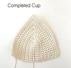 a crocheted white hat is shown with the words completed cup on it