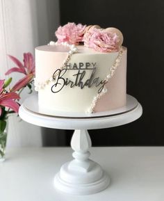 a white cake with pink flowers on top and the words happy birthday written on it