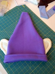 a purple hat sitting on top of a cutting board next to a pair of scissors