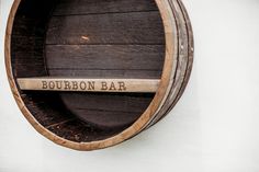 a wooden barrel with the word bourbon bar on it's side hanging from a wall