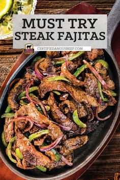 a skillet filled with meat and vegetables on top of a wooden table