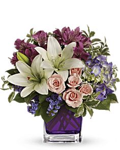 a purple vase filled with lots of flowers on top of a table next to a piece of cake