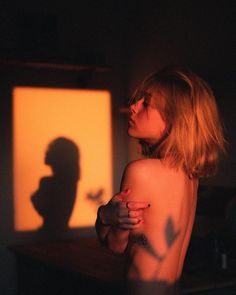 a naked woman standing in front of a screen with the shadow of a man's head on it