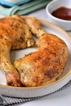 two pieces of chicken on a plate with dipping sauces in the bowl next to it