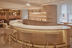 an empty bar with white chairs and lights on the wall behind it in a restaurant