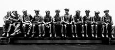 a group of people sitting next to each other on top of a metal bench in front of a building