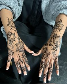 a woman's hands with hendix and flowers on them, both covered in black ink