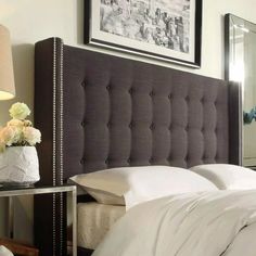 a bed with white sheets and pillows in a bedroom next to a framed photograph on the wall