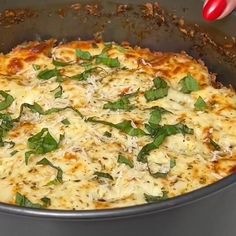 a close up of a pizza in a pan on a stove top with basil and cheese