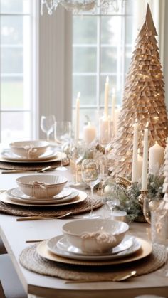 a dining room table set for christmas with candles, plates and napkins on it