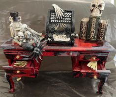 an old desk has skeleton decorations on it and is decorated with books, candles, and skulls