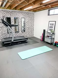 an exercise room with treadmills, yoga mat and wallpaper on the walls